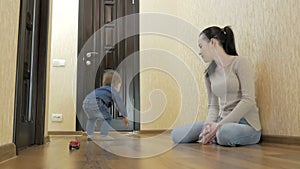 Toddler playing with mom toy cars sitting on the floor