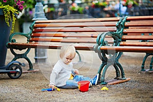 Toddler playing with sand molds, bucket and shovel