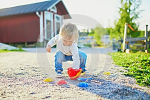 Toddler playing with sand molds, bucket and shovel