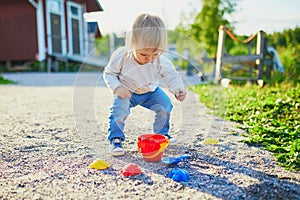 Toddler playing with sand molds, bucket and shovel