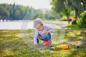 Toddler playing with sand molds, bucket and shovel, making mudpies and gathering small stones