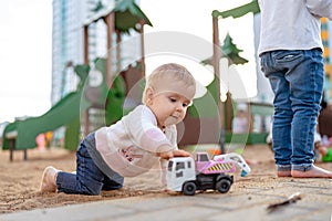 Toddler playing with toy car. Adorable little girl having fun on playground.