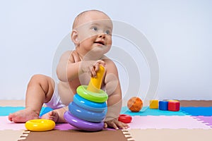 A toddler plays with a multi-colored pyramid of rings. Development of thinking and hand motor skills