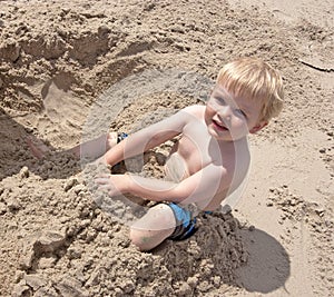 Toddler plays in sand at the beach