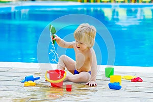 Toddler by the pool with toy bucket set