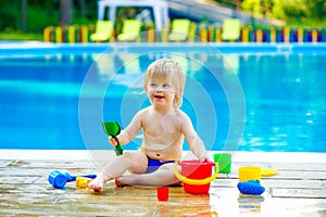 Toddler by the pool with toy bucket set