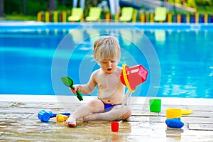 Toddler by the pool with toy bucket set