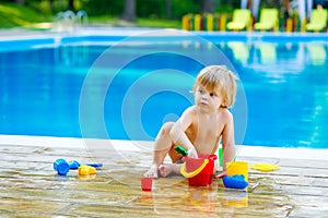 Toddler by the pool with toy bucket set