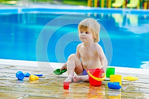 Toddler by the pool with toy bucket set