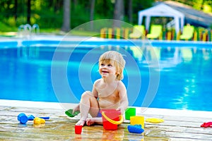 Toddler by the pool with toy bucket set