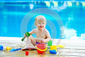 Toddler by the pool with toy bucket set