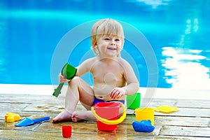 Toddler by the pool with toy bucket set