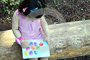 Toddler reading a book outdoors.