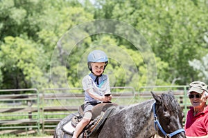 Toddler with a Safety Helmet on Goes on a Pony Ride at a Local Farm with his Horse Being Led Grandfather
