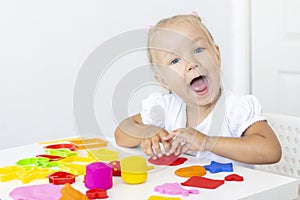 Toddler sculpts from colored plasticine on a white table. photo