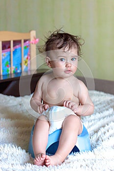 Toddler sitting on chamber pot in the room