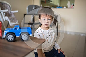 Toddler sitting with his toy cars in the living room closeup portrait