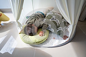 Toddler sleeping in a kids tent at home