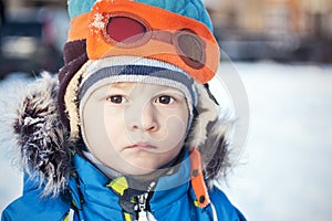 Toddler in snow winter in fur coat and pilot hat