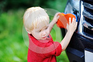 Toddler son washing fathers's car