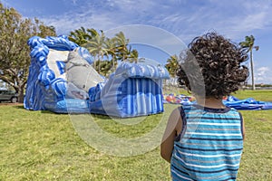 A toddler stands very still watching a bounce house inflate