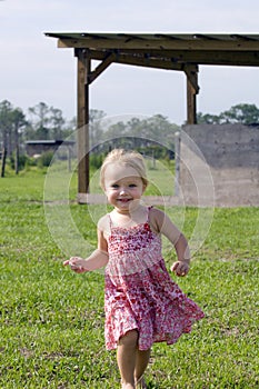 Toddler in sundress running on farm photo