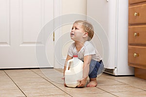 Toddler trying to lift up gallon of milk. copy space