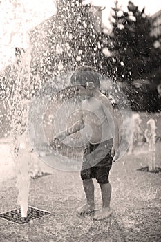 Toddler walking in a splashing water fountain