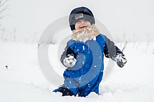 toddler with warm clothes playing in winter with snow