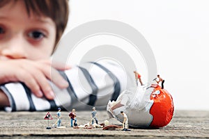 Toddler watching miniature people breaking an egg