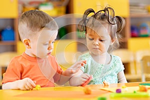 Toddlers boy and girl playing at table with educational toys. Children infants at home or daycare.