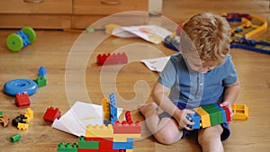 Toddlers build a tower in kindergarten. Child playing with colorful toys. Funny curly baby boy with educational toy