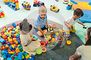 toddlers enjoying building blocks, cars, ships and other plastic toys in kindergarten