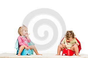 adorable toddlers in superhero capes sitting on potties photo