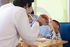 Todler playing cake with his father at cafe