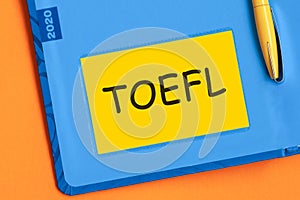 Toefl the word is written in black letters on the yellow paper for notes