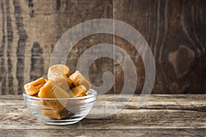 Toffee caramel candies in a crystal bowl on wood