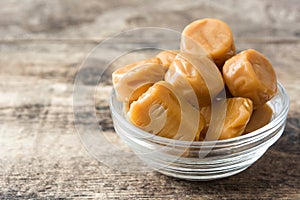 Toffee caramel candies in a crystal bowl on wood