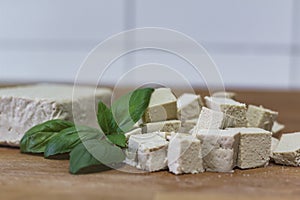 Tofu block and cubes of tofu on wooden cutting board