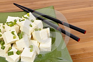 Asian vegetarian food : Tofu cubes with chopsticks close up