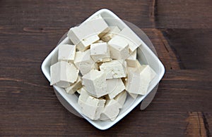 Tofu cubes on wooden square bowl on top