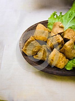 Tofu filled with meatballs and lettuce on wooden plate