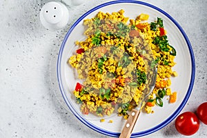 Tofu scramble with vegetables in a white plate, top view. Vegan Alternative fried eggs