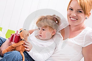 Together: daughter sitting on mother's lap with present isolated