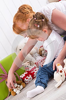 Together: daughter sitting on mother's lap with presents on birt