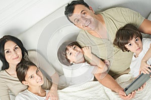 Together at home. Portrait of happy latin famile, little kids and parents smiling at camera while spending time together