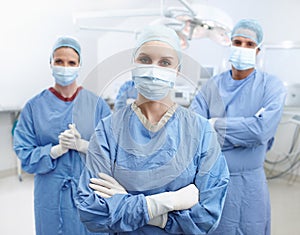 Together we make miracles. Portrait of four surgeons wearing hospital scrubs, face masks and protective gloves in an