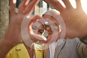 Always together. Portrait of cute and cheerful senior couple making a heart shape with their hands and fingers while