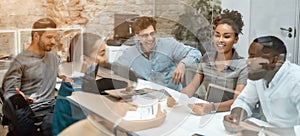 Together we are powerful. Group of young business people discussing new project while sitting on the office table behind photo