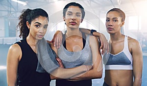 Together we stand undefeated. Portrait of three young sportswomen standing and posing in the gym.